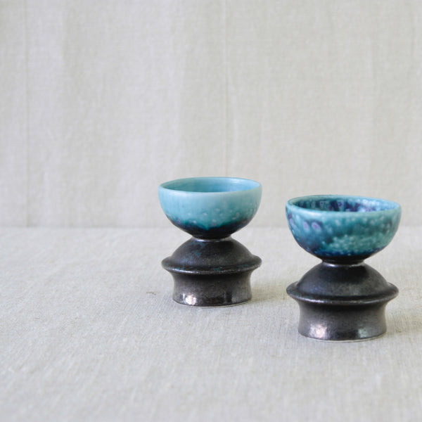 Liisa Hallamaa brown stoneware candleholders, with restrained chocolate-brown exteriors contrasting with intensely coloured blue interiors.