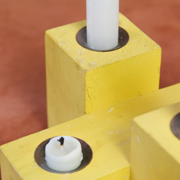 Detail of painted wooden yellow blocks of wood made into a candle holder by Erik Höglund