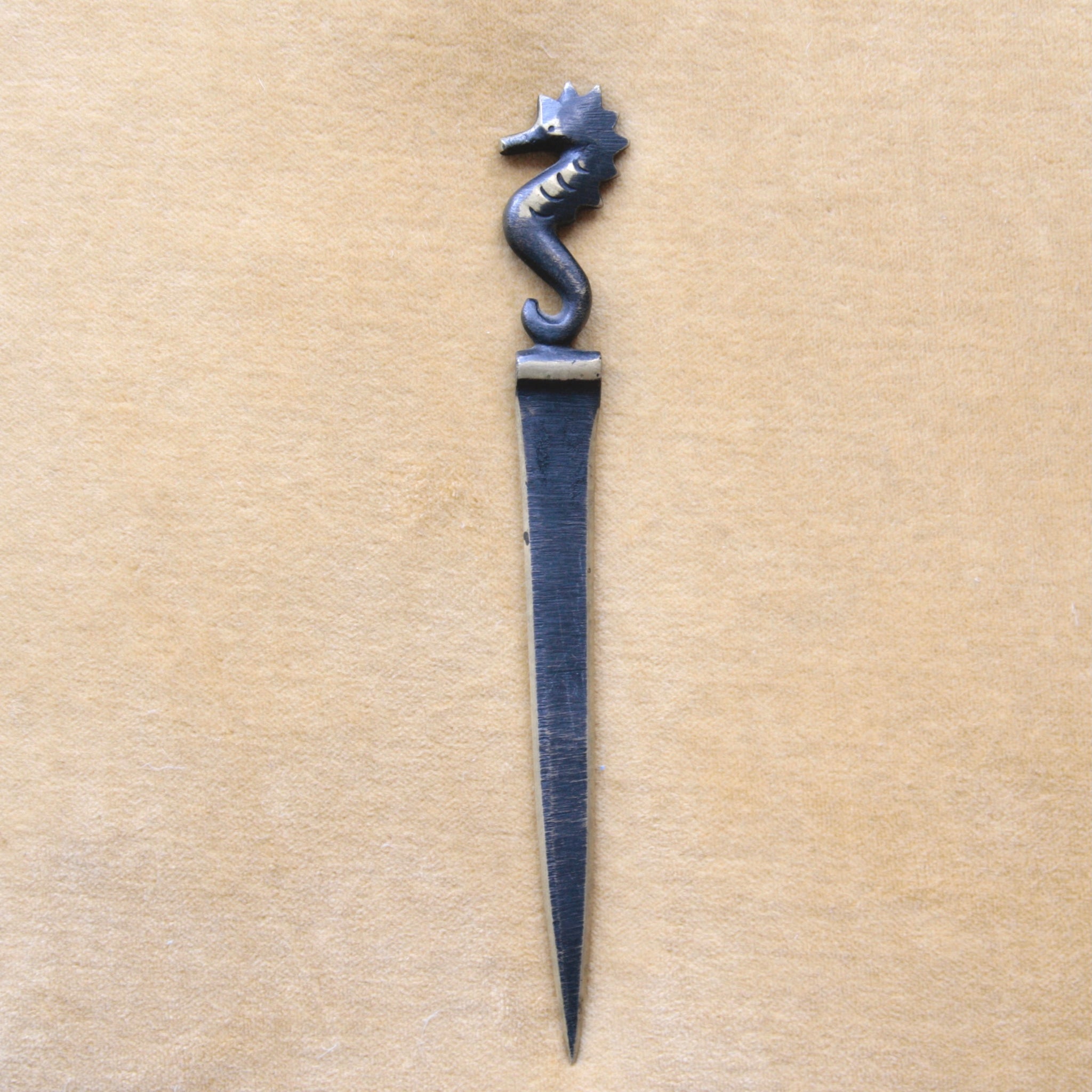 Decorative letter opener with seahorse design on a golden yellow background. Modernist Walter Bosse seahorse letter opener, made by Herta Baller, Austrian mid-century brass collectible.