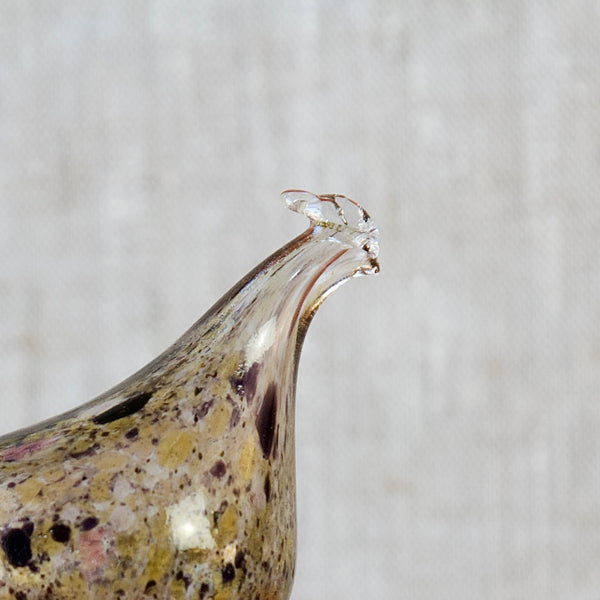 A close up of the head and face of a glass hen belonging to a model kf254 hen bottle by Nuutajärvi Notsjö, Finland. This is an iconic piece of Finnish design created by the renowned designer Kaj Franck.