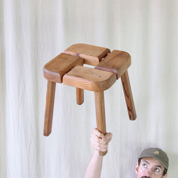 Fun mood image of Sam holding in the air a vintage Finnish sauna stool by Olof Ottelin, constructed entirely from solid pine using traditional timber joinery and exposed wooden dowels.