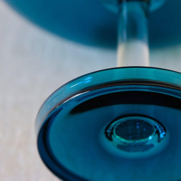 Detail of a Riihimäki Harlekiini footed bowl by Nanny Still, showing its vibrant turquoise glass and precise construction.