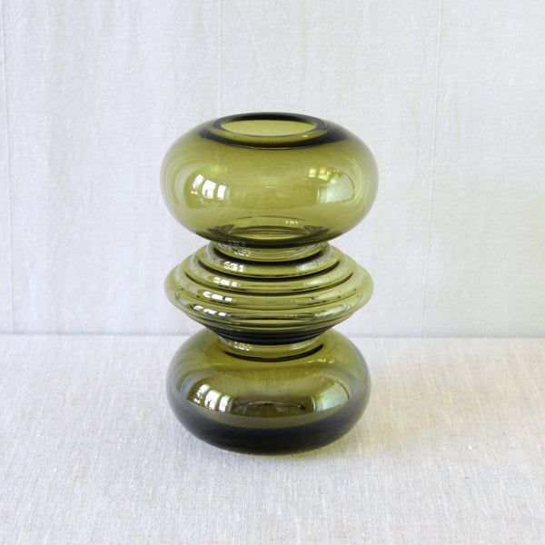 Nanny Still ribbed olive green glass vase, with the deep earthy colour gathering in darker tones around its textured centre.
