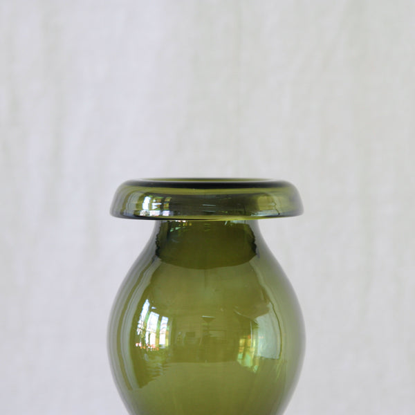 Detail of 1960s Finnish sculptural glass vase by Nanny Still, with an elongated olive green body and rhythmic hooped form.
