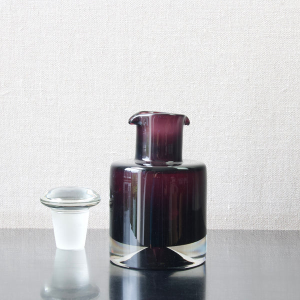 Nanny Still rare glass decanter with double lip. The heavy object is dark purple and features a chunky stopper