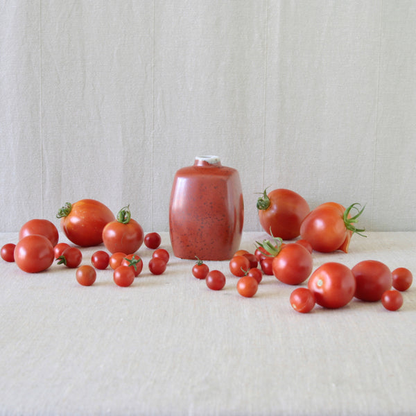 Mood shot of Nils Thorsson's jernrød vase displayed alongside red tomatoes