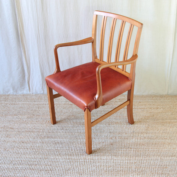 Top down view of the red leather upholstery and piping on an Ole Wanscher Model 1675 chair, carefully outlining the exposed beech frame.