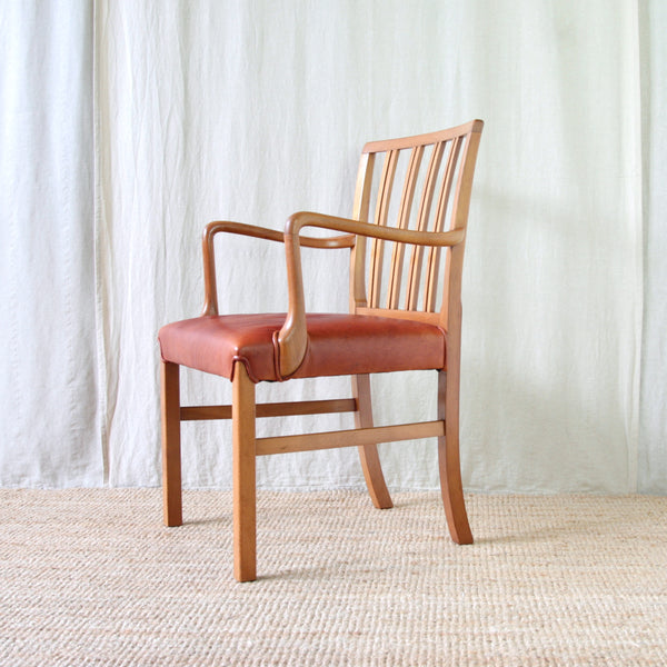 Vintage Fritz Hansen armchair designed by Ole Wanscher, with curved wooden arms, paired back spindles and newly upholstered red leather seat.