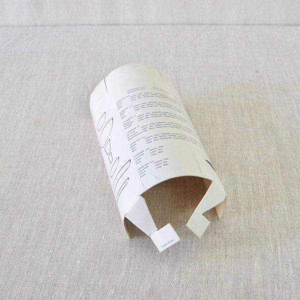 Top down view of original packaging to a Kaj Franck 'Party-set'. Photo shows the cylindrical original cardboard tube with information on Franck's designs, including model numbers and the names of colours.