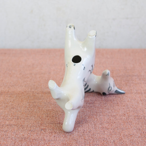 White ceramic animal figurine on a pink surface with a white background. Photo shows the underside of a rare vintage unicorn figurine by Susan Parkinson, two feet feature the British studio potters makers marks.