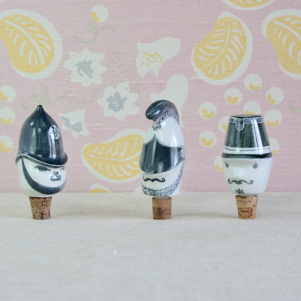 Mid-century porcelain bottle stopper trio designed by Susan Parkinson and Guy Neale, with brightly hand-painted faces and distinctive uniformed characters.