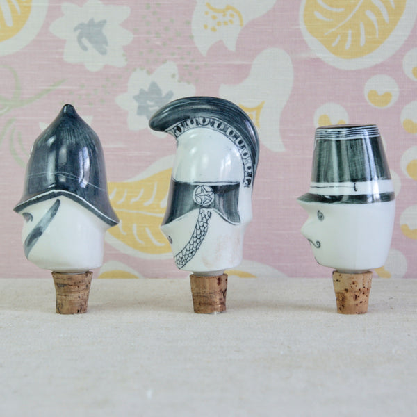 Three vintage Parkinson Pottery cork bottle stoppers depicting uniformed characters, including a Policeman, helmeted Cavalry Officer and moustached French Gendarme.