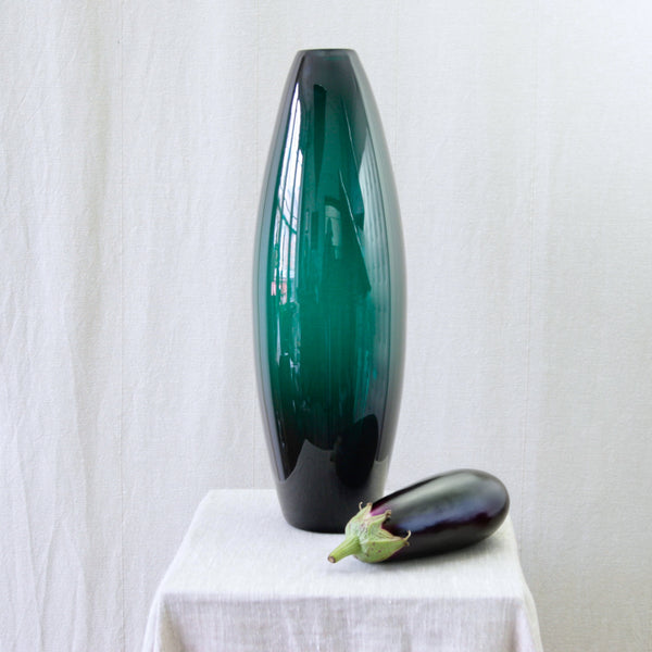 Per Lütken Holmegaard model 17660 vase in saturated dark green glass, the largest elliptical vase from the Grønland series. Aubergine for scale.