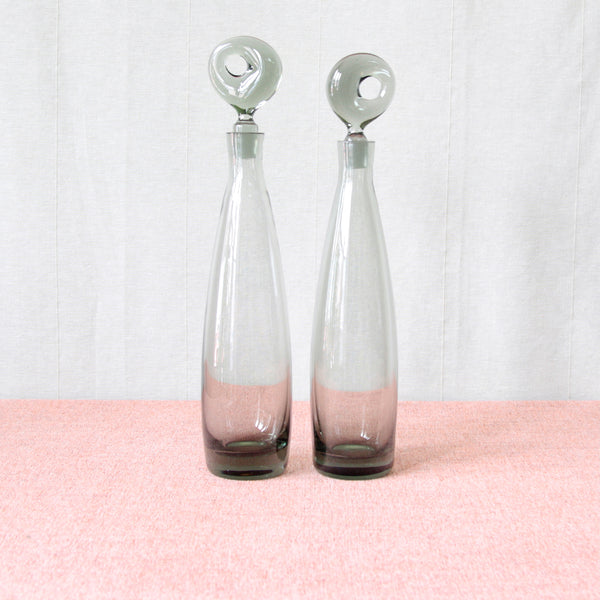 Two vintage glass decanter bottles with unique freeform stoppers. Tall and slender 1950’s design by Per Lütken. Model name 'Aristokrat’. Hand blown in organic Modernist “Smoke” grey coloured glass, mid-century Danish design produced by Holmegaard glassworks.