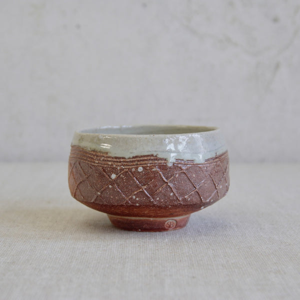 Phil Rogers pottery tea bowl combining Anglo-Oriental design, lattice impressions, and dual glaze finishes.