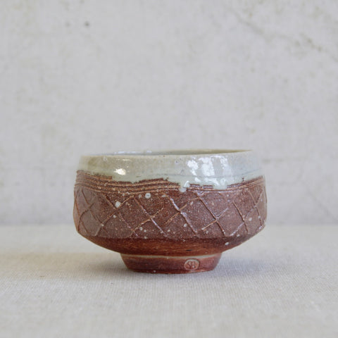 Lead image of a Phil Rogers stoneware chawan with footed form and expressive lattice-impressed exterior design. Fantastic British studio pottery.