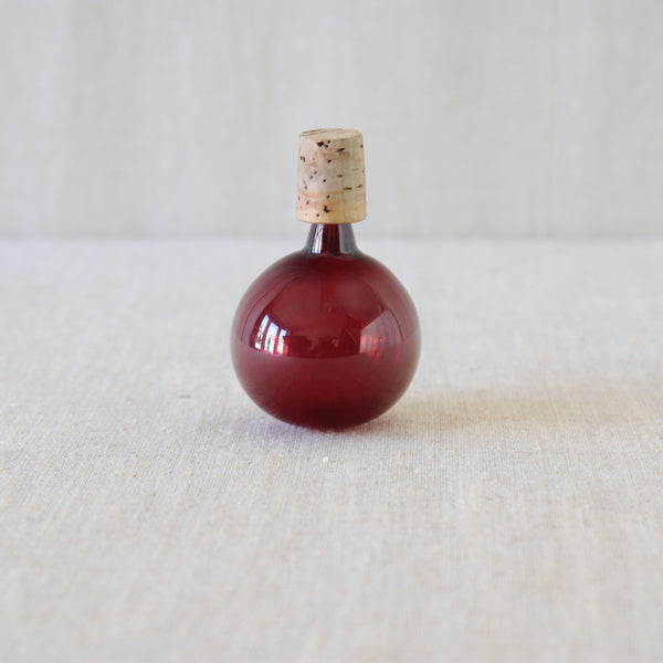 A round glass bottle stopper in deep burgundy red. This decanter stopper is from a Kaj Franck Kremlin Kellot /Kremlin Bells decanter. Photographed for UK gallery Art & Utility, who specialise in Scandinavian design.