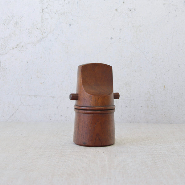 A mid-century teak “mouthpiece” pepper grinder designed by Jens Quistgaard for Dansk Designs, sought after for its sculptural elegance.