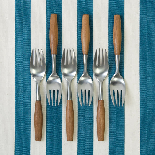6 large dinner forks by IHQ Jens Harald Quistgaard. The teak and stainless steel cutlery is atop a blue and white striped fabric. A striking image showing how fresh and chic MidCentury Scandinavian design still is.