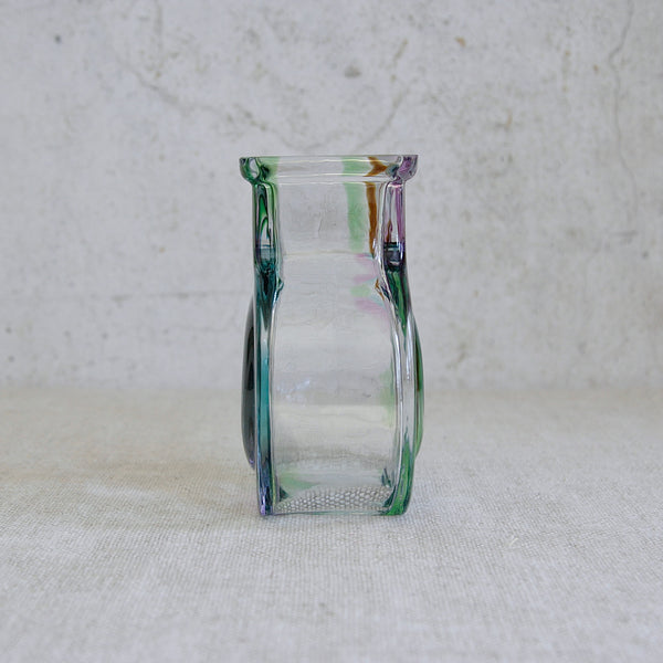 Side view of a glass vase with green and purple swirls on a white background. Finnish collectible glass vase by Helena Tynell, Bora Bora design, reflecting the evolution of Scandinavian modern glass in the 1970s.