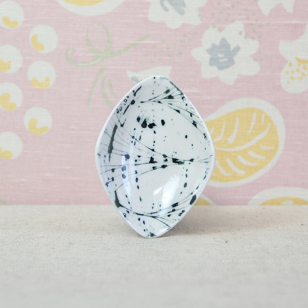A biomorphic glossy ceramic dish with a white base and black abstract splatter and line pattern. Design by Susan Parkinson for the Richard Parkinson Pottery in Brabourne Lees, Kent. Collectible 1950s British design
