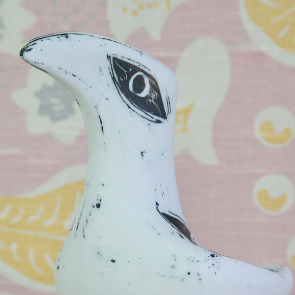 A close-up of a white ceramic bird figurine with black speckled details and a stylized eye. 1950s British studio ceramics, Susan Parkinson Large Bird with loose markings, spots and spontaneous splashes