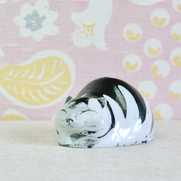 A glossy ceramic cat figurine with a black and white tabby pattern, Susan Parkinson piggy bank design with a wonderfully rounded, sculptural form