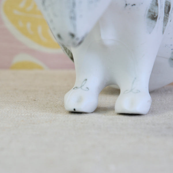 Close-up of the feet of a white ceramic Susan Parkinson Sheep with abstract wax-resist squares, ovals, curls, splashes and spots