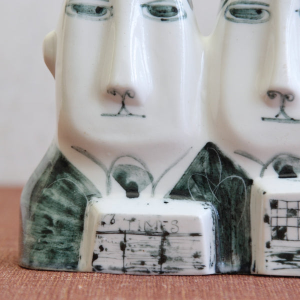 Detail of a commuter reading the Times on a museum-level British Modernist ceramic sculpture by Susan Parkinson, influenced by Picassoettes approaches to form and surface.