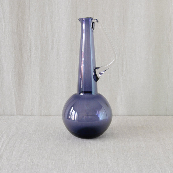 Lilac 1749 glass carafe by Tamara Aladin for Riihimäki, with a tall tapering neck rising dramatically from a rounded spherical body. Available to buy in the UK at Art & Utility.