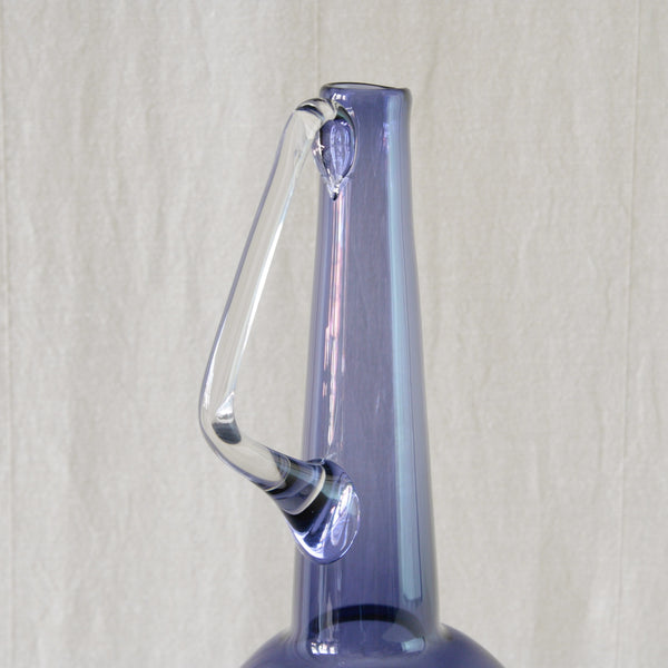 Tamara Aladin model 1749 carafe with an elegant hand-applied triangular glass handle contrasting with its rounded lilac body.