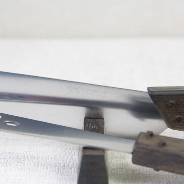 Close up showing the etched makers marks on a cutlery set designed by Tapio Wirkkala. The branding reads 'HACKMAN FINLAND STAINLESS TAPIO WIRKKALA'.