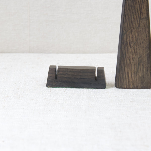 Zoomed in image of a small geometrically shaped block stand, belonging to a carving utelsils set by Tapio Wirkkala. The set was produced by Finnish steel manufacturer Hackman, using historic Black Oak salvaged from Vasa, a 17th century Swedish warship.