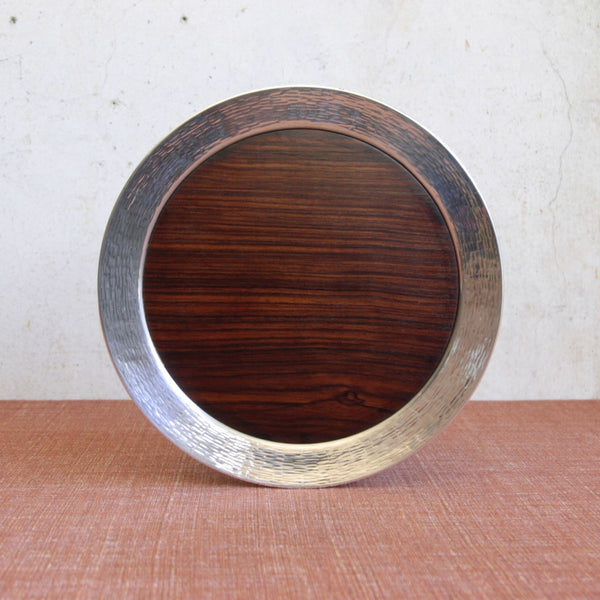 Head on shot of a rare TWT142 Tapio Wirkkala circular tray combining hand-tooled silver band and macassar ebony centre. Made by Kultakescus. For sale in the UK from Nordic design gallery Art & Utility.