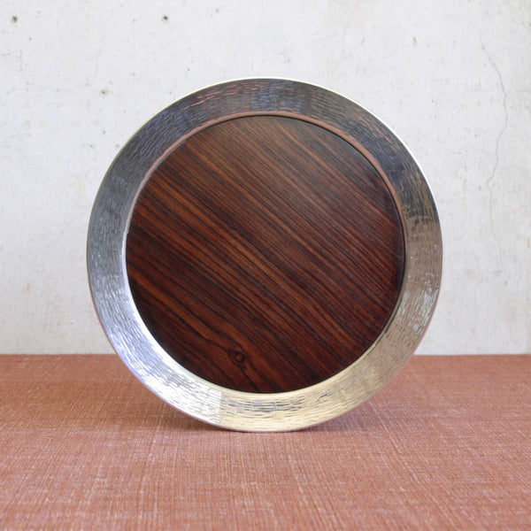 Straight on shot of an elegant circular Scandinavian silver tray by Tapio Wirkkala with exotic ebony insert