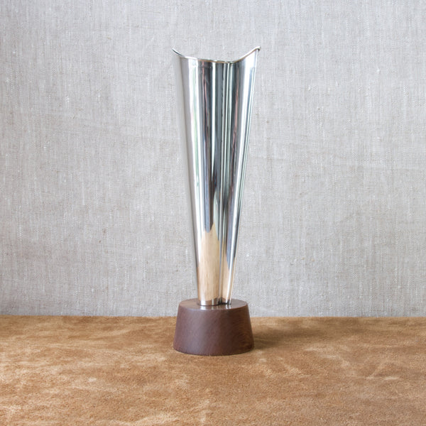Tall gleaming solid silver Finnish vase by Tapio Wirkkala for Kultakeskus Oy. The angular vase stand atop a round teak wood base. The Nordic design is from 1960.