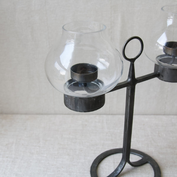 A picture looking into a candelabrum with a clear glass shade in the form of a tulip flower. The design is by the prolific Swedish designer Bertil Vallien. Buy this collectible piece of mid twentieth century design and many others from Art and Utility, London. Who ship to Japan and all other countries in East Asia.