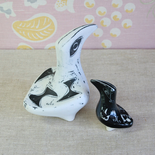 Top down view of two decorative bird figurines, one large white with black abstract markings and one small black with white markings. Both collectable 1950s British ceramic design by Susan Parkinson. For sale in the UK from Art & Utility.