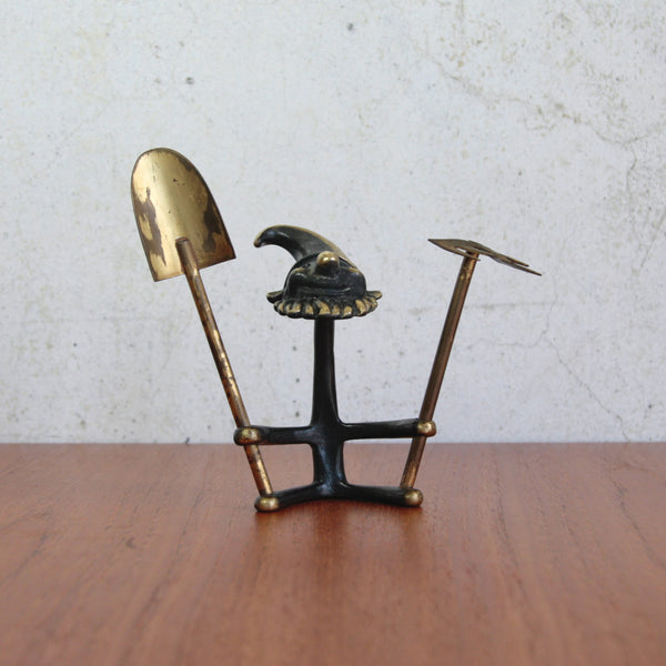 Vintage 1965 Walter Bosse brass gnome, cheerful seated figure with spade and rake.