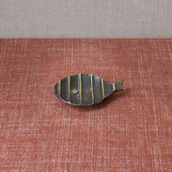 Top down image of a Walter Bosse fish tray by Herta Baller. The black and yellow fish tray is far away and sits on a textured red tablecloth. 