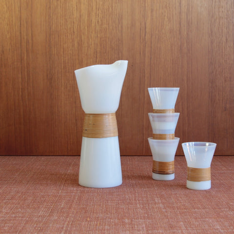 An Opaline milk-glass carafe and 4 drinking glasses designed by Jacob Bang for Kastrup Glassworks, the set displays clean conical forms which contrasts beautifully with the natural rattan grip. Danish Modernism and Functionalism at its best.