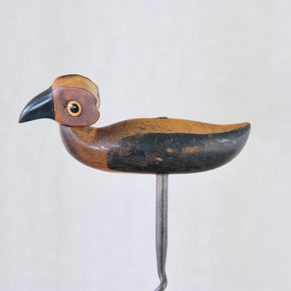 Full-length view of a YZ bird corkscrew showing the steel screw extending beneath the carved wooden body like improbably long bird legs.