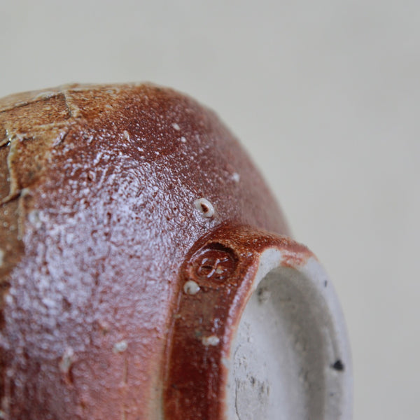 Close-up of a Phil Rogers textured ceramic chawan with footed base and contrasting salt-glazed exterior.