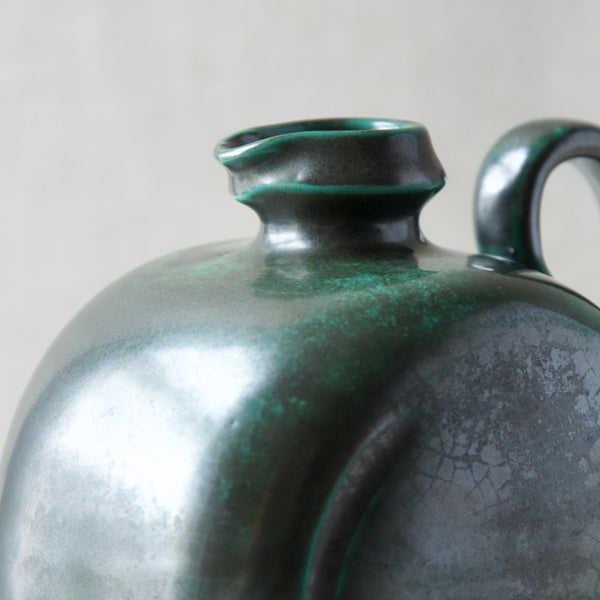 Close up showing the lighter turquoise green colour showing through at the edges of this dark green copper glaze jug designed by Harald Östergren, 1920s.