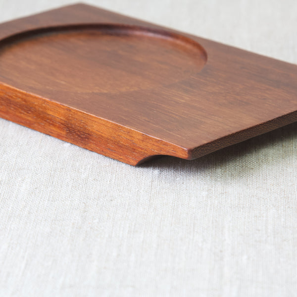Detail showing the grain of the high quality teak wood used in a design by A round glass hors d'oeuvre dish on a rectangular wooden tray designed by Saara Hopea for Nuutajärvi Glassworks. this mid-1950s collectable Nordic design and many other available to view and buy in South West London at Art & Utility.