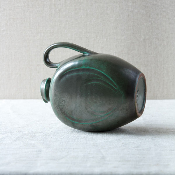 A handled pitcher in green designed by Harald Östergren for Upsala Ekeby in Sweden in the 1920s.