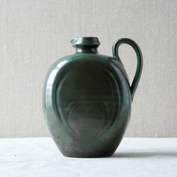Head on shot of an Upsala Ekeby dark green glazed ceramic handled jug designed by Harald Östergren circa 1925.