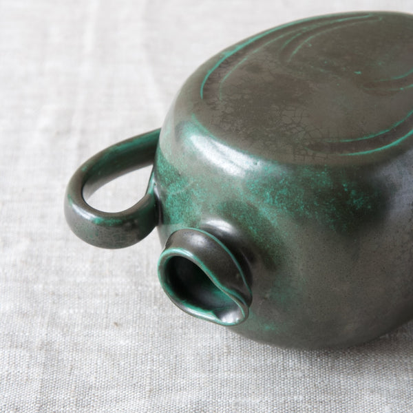 A Harald Östergren ceramic jug with handle laying on its side, image shows the complex complexion of the copper oxide glaze. Great 1920s Art Deco Scandinavian design.