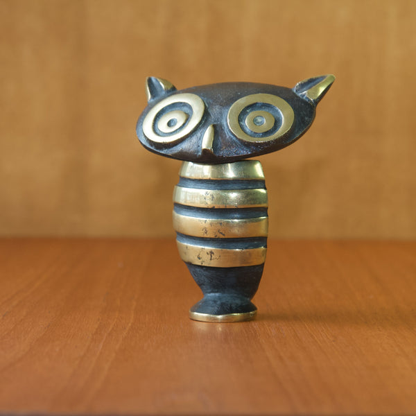 Detail showing the striped body of a freestanding Walter bosse owl corkscrew bottle opener. The lower sections of the items surface are black patinated whilst the raised or higher areas are polished to reveal the base material which is brass.