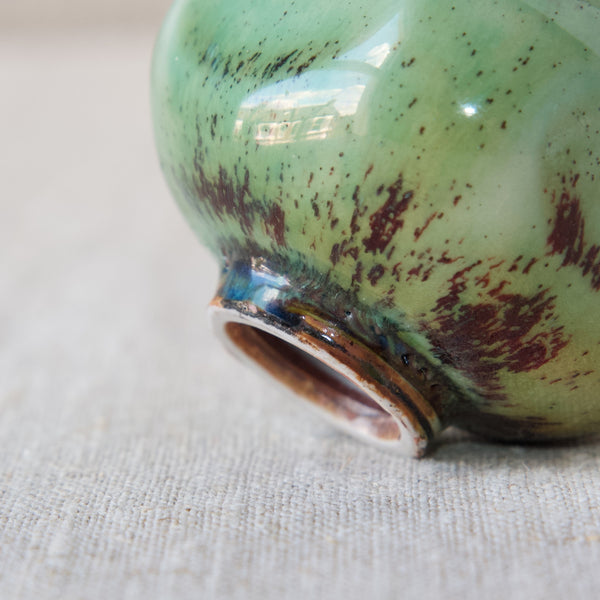 Close up image showing the insane amount of interest and detail in an intricately glazed turquoise green ceramic vase by Berndt Friberg. The glaze also features splashes or speckles of sang de boeuf deep oxblood red.